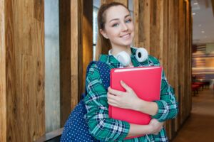 Smiling female international student holding study materials